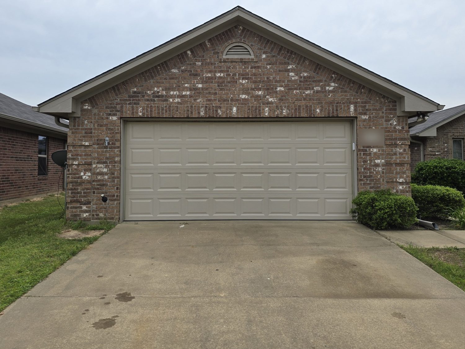 The same brick house with a new tan raised-panel garage door
