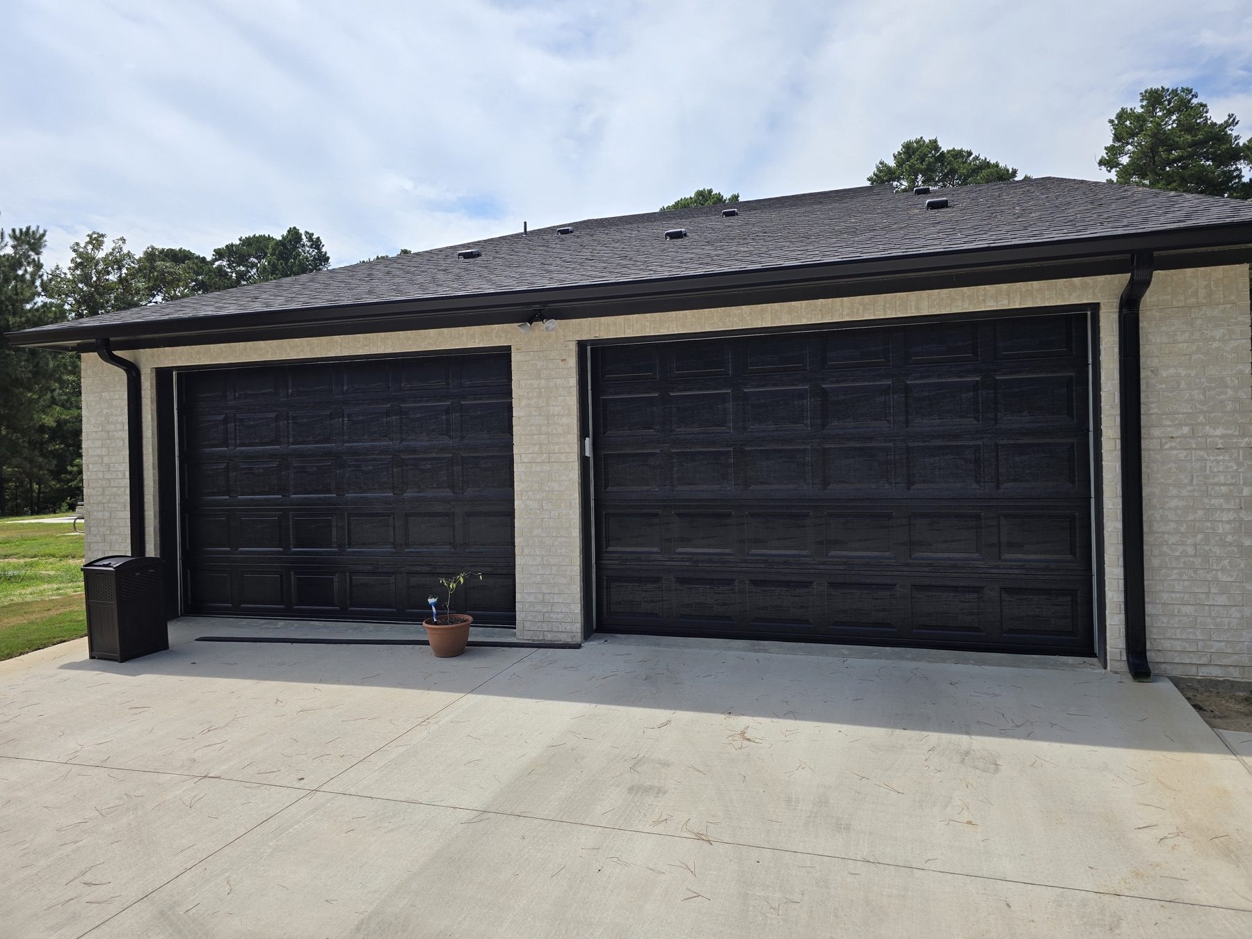 Two dark carriage-style garage doors set in brick