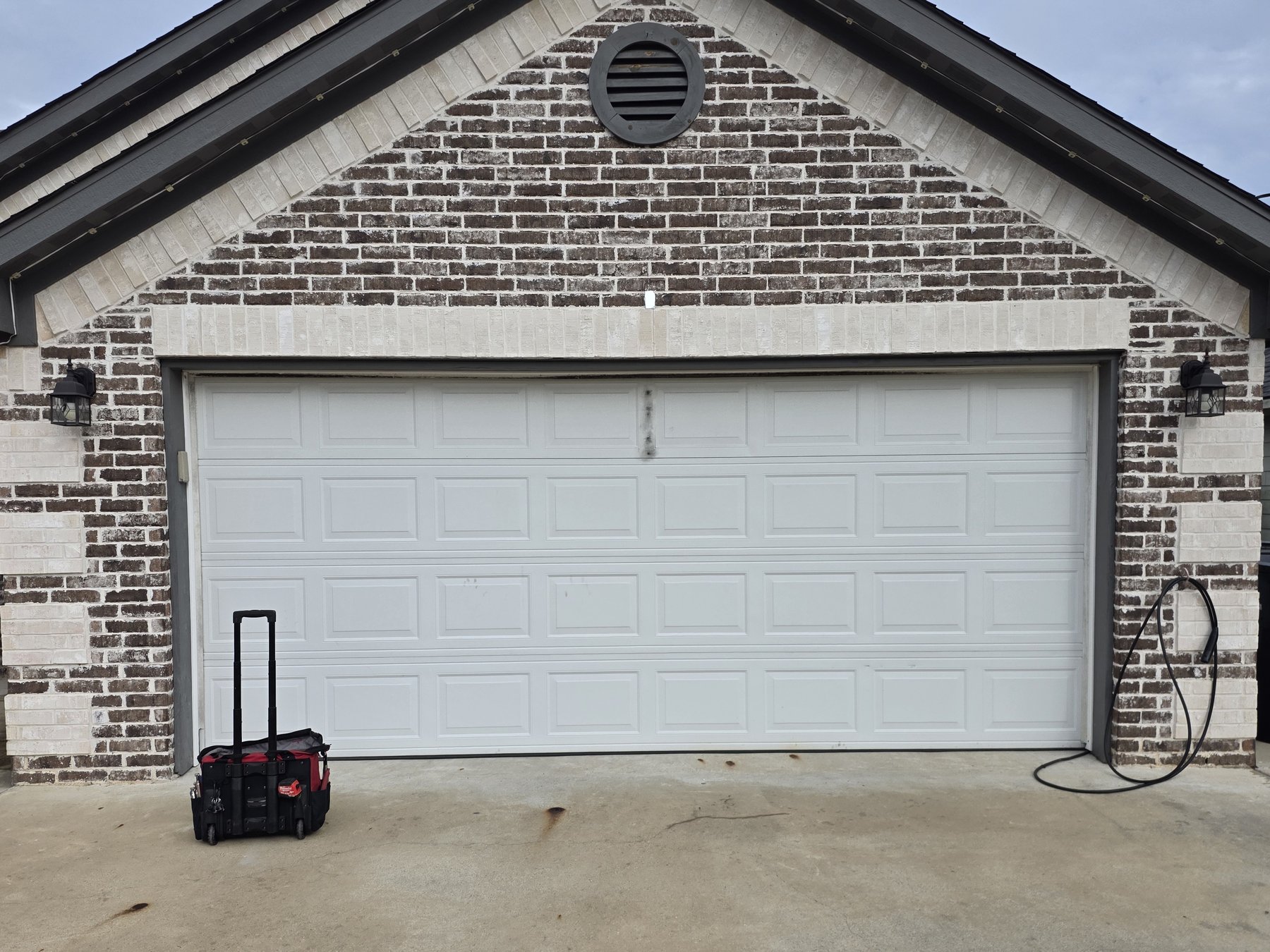 The same brick house with the white garage door back on track and closing straight
